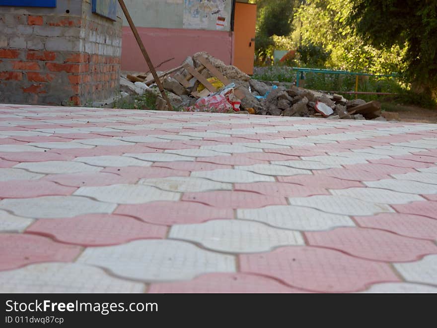 Close-up of new old-style pavement of figured stoneblocks and heap of construction rubble. Close-up of new old-style pavement of figured stoneblocks and heap of construction rubble