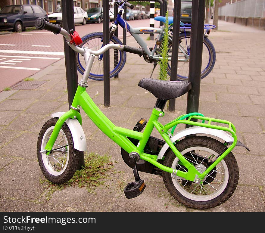 An apple green child's bicycle, parked in the street