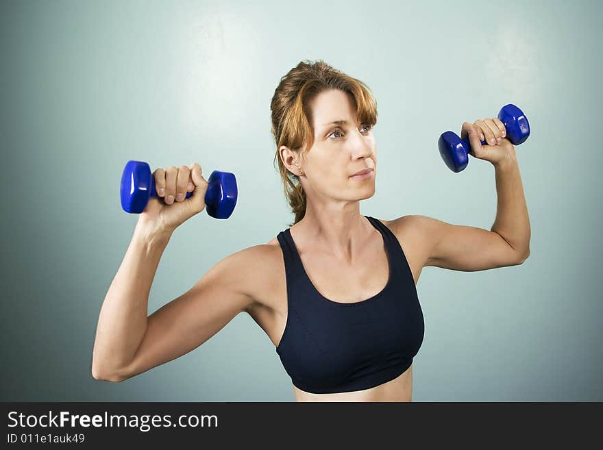 Pretty athletic woman working out with dumbbells. Pretty athletic woman working out with dumbbells