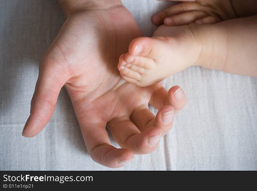 Mother is holding small baby arm and foot