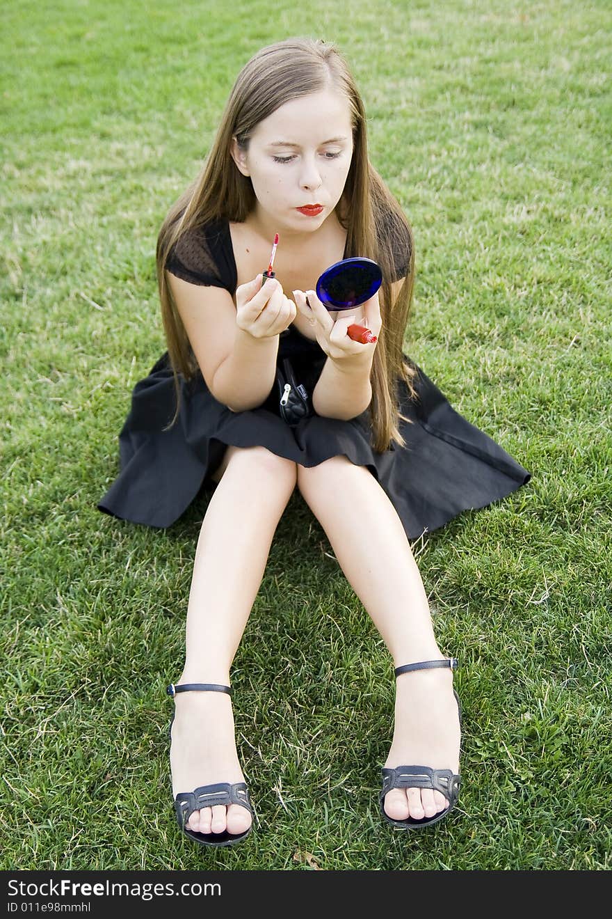 Girl doing makeup on meadow