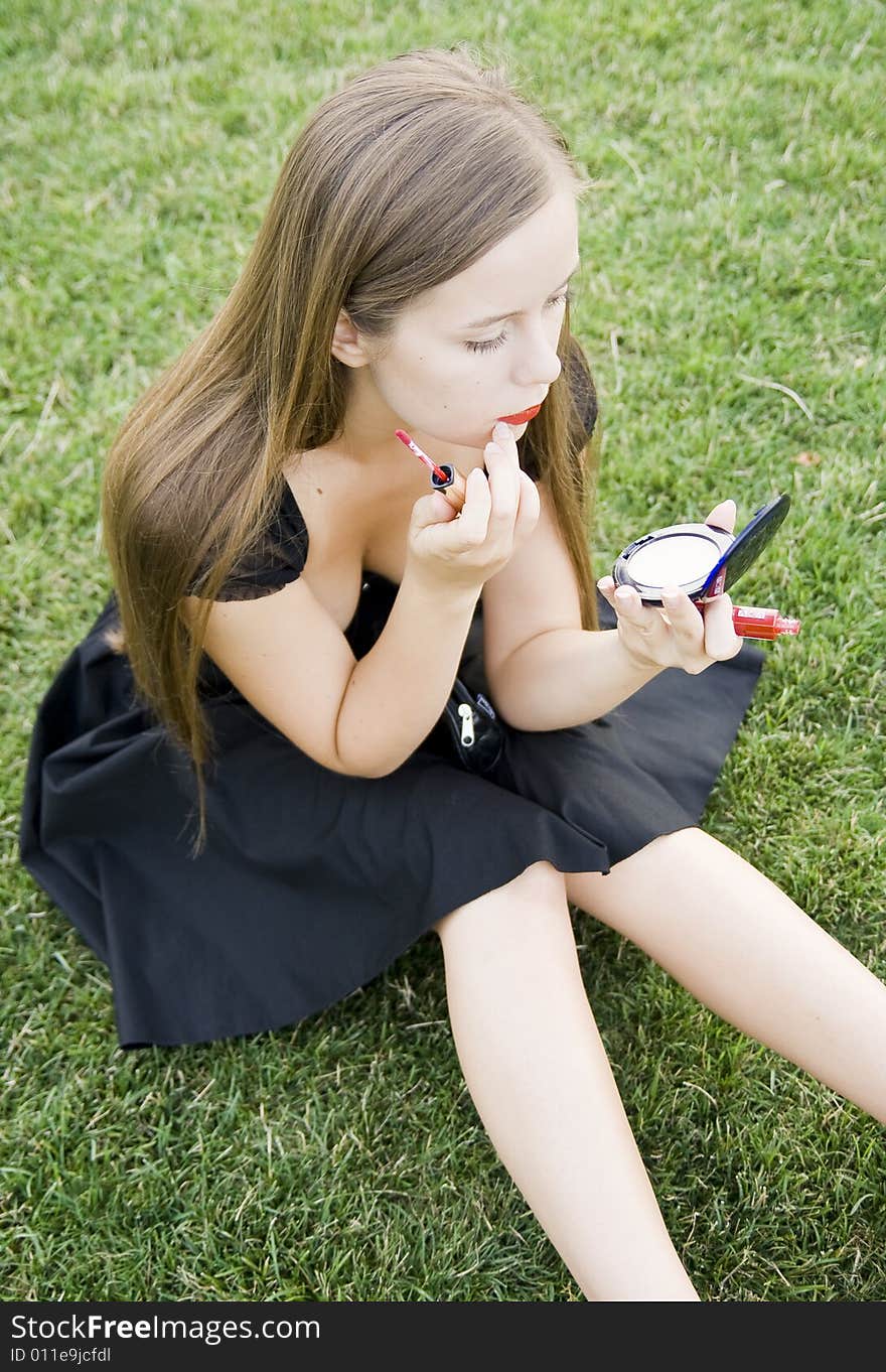 Girl doing makeup on meadow