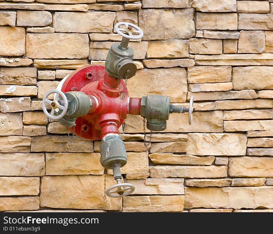 A red fire hydrant on a rock masonry wall. A red fire hydrant on a rock masonry wall