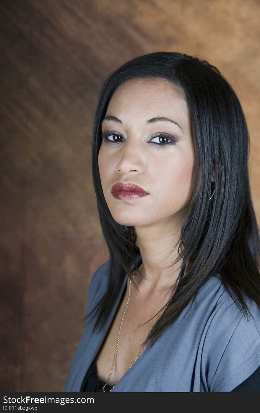 Portrait of a dark haired lady, head and shoulders, facing left and looking at camera. Portrait of a dark haired lady, head and shoulders, facing left and looking at camera.