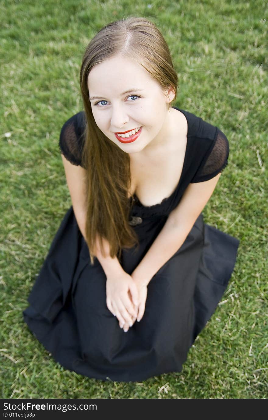 Smiling girl with red lips on green grass