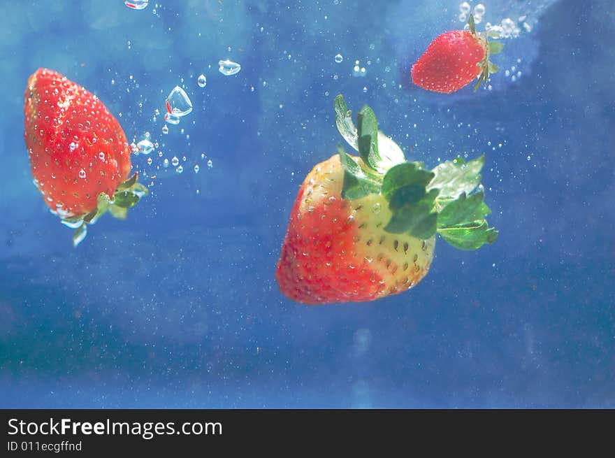 Strawberries falling in deep blue water. Strawberries falling in deep blue water