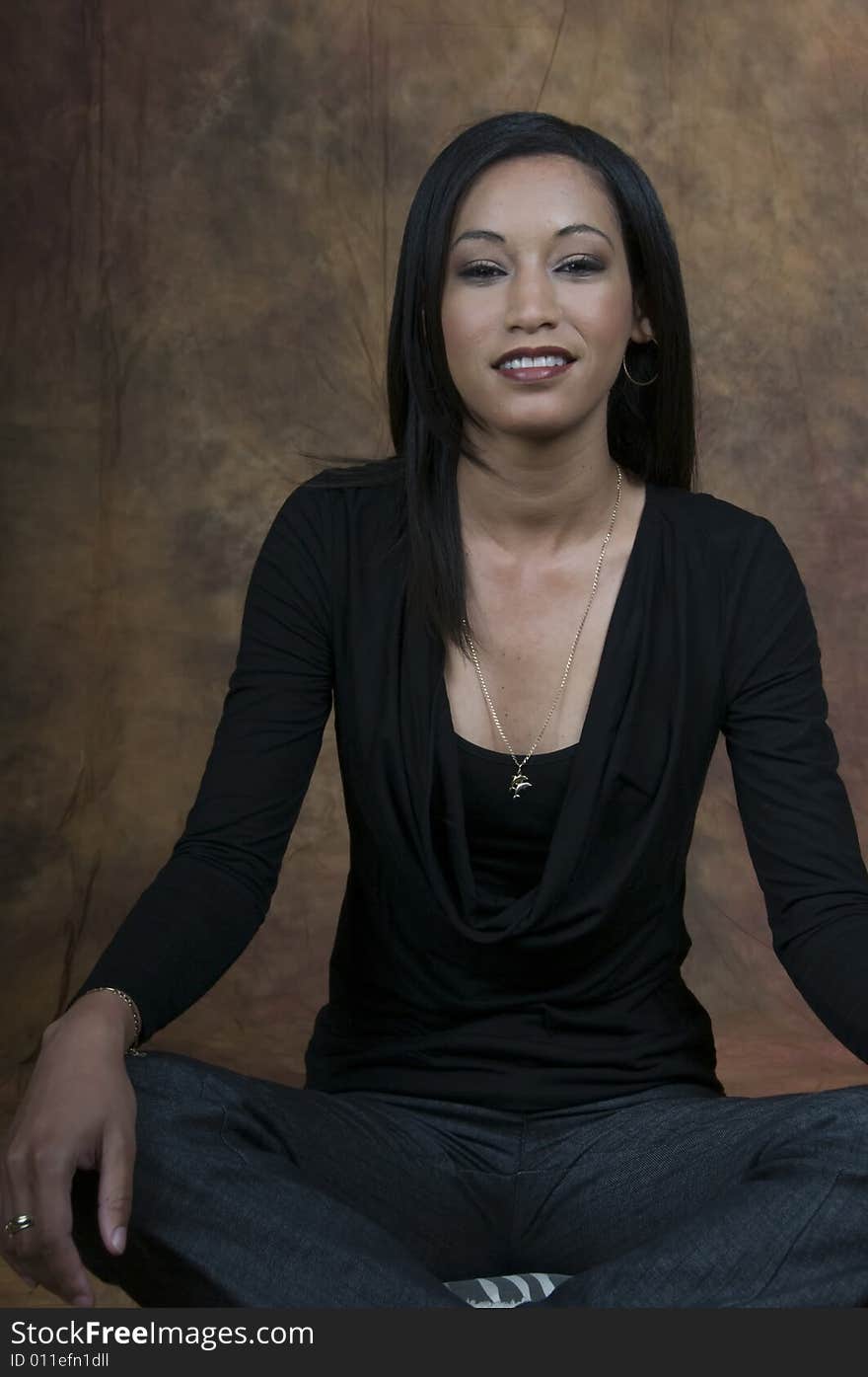 A young lady sitting cross legged smiling. A young lady sitting cross legged smiling.