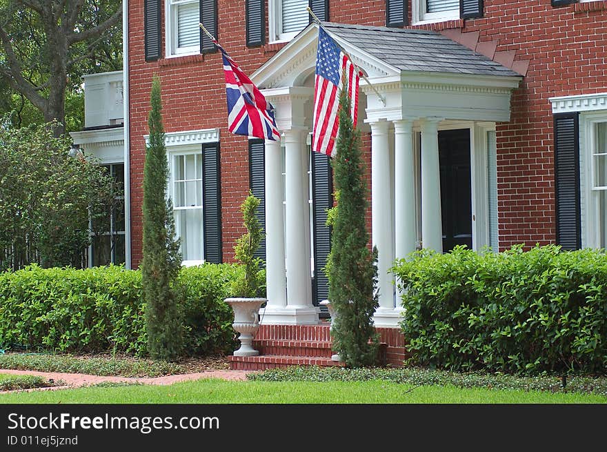 American flag and Union Jack flying in front of brick house. American flag and Union Jack flying in front of brick house.