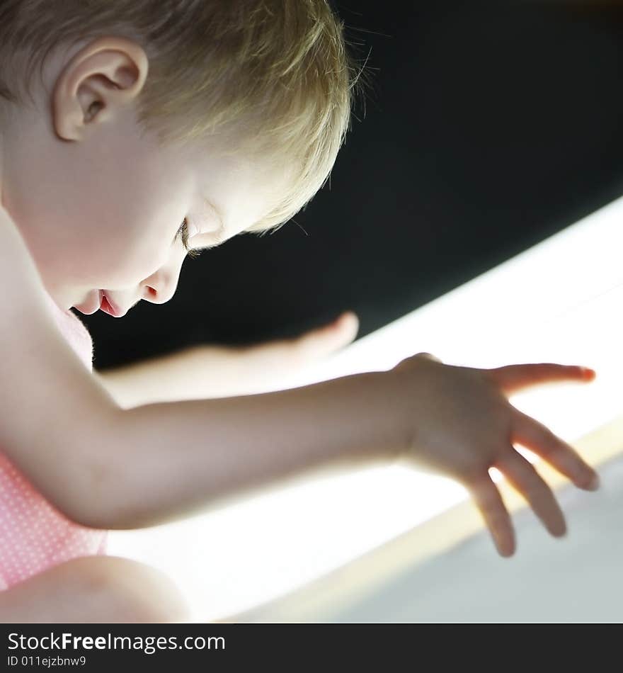 Profile of a baby girl looking very interested to a bright light close to her face. Profile of a baby girl looking very interested to a bright light close to her face