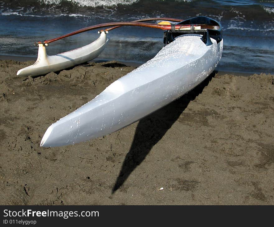 White sport Polynesian dugout on a black sand beach. White sport Polynesian dugout on a black sand beach