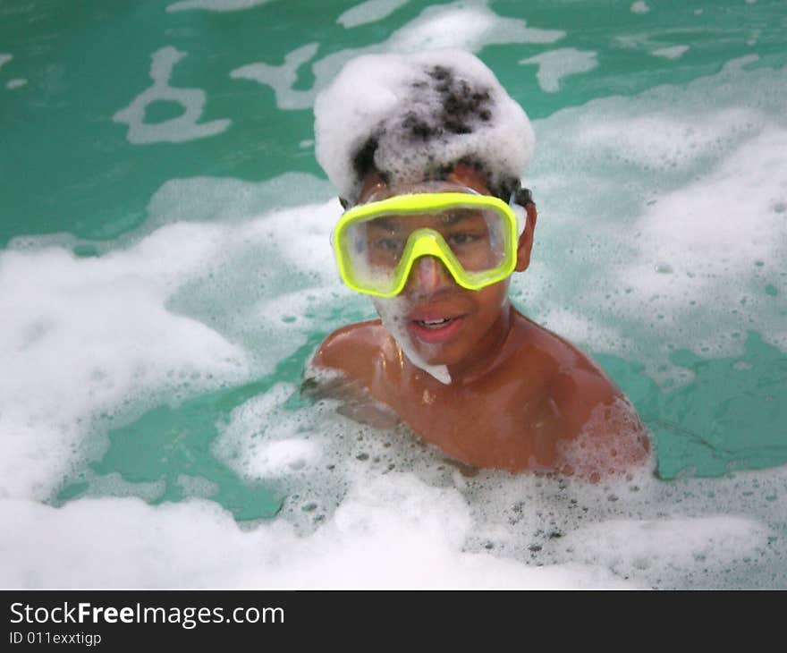 A picture of a black boy in a pool with a goggles or a swim mask with bubbles around him. A picture of a black boy in a pool with a goggles or a swim mask with bubbles around him.