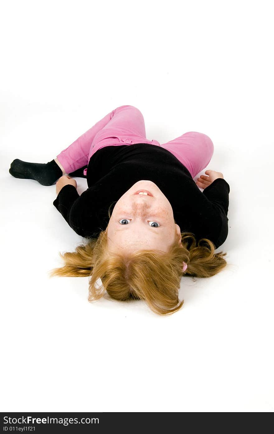 Little girl is laying on floor looking towards the camera