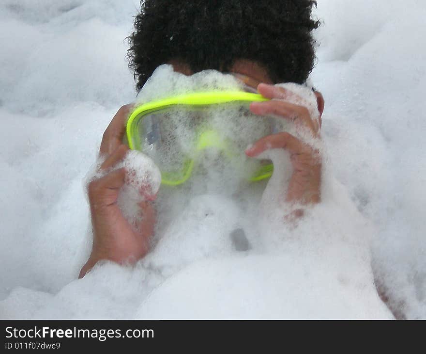 A picture of a black boy with a swim mask or goggles covered in lots of bubbles. A picture of a black boy with a swim mask or goggles covered in lots of bubbles.