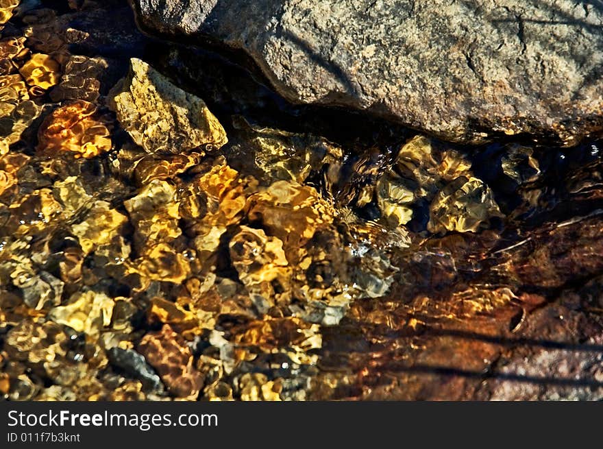 Pebbles in a mountain stream with flowing crystalline water. Pebbles in a mountain stream with flowing crystalline water