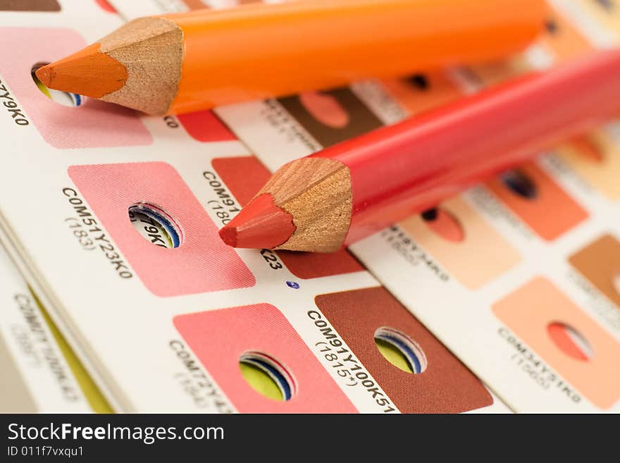 Orange and red pencils on cmyk color bars. Orange and red pencils on cmyk color bars