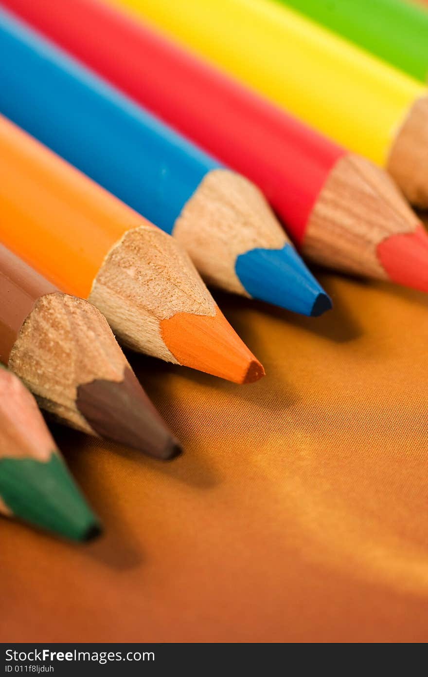 School and office articles: coloured pencils on brown background. School and office articles: coloured pencils on brown background