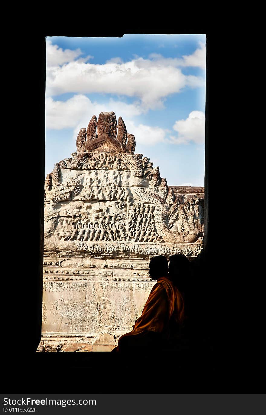 Silhoette of monk sitting in window frame on old temple background