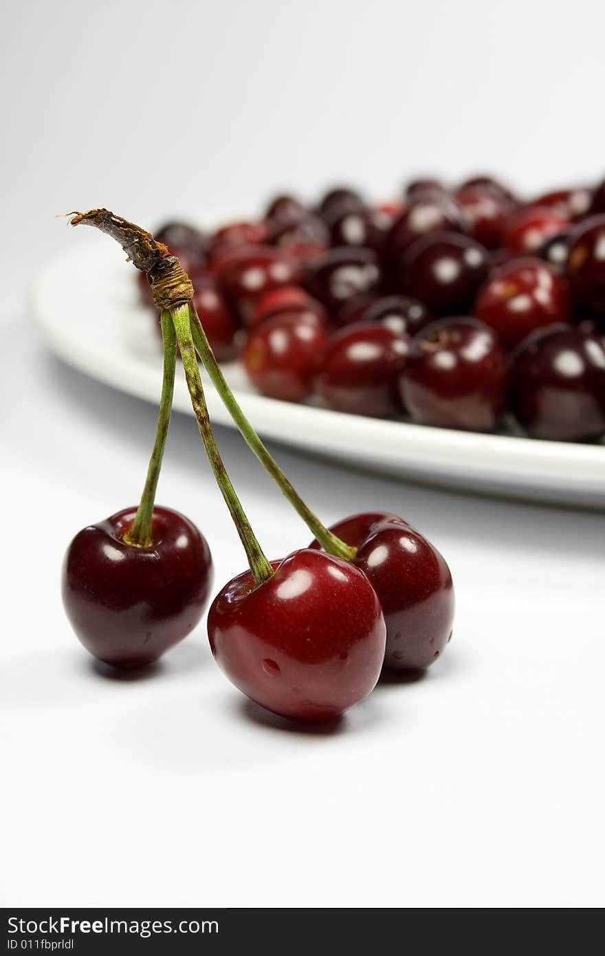 Three red cherries and cherries in white plate. Three red cherries and cherries in white plate