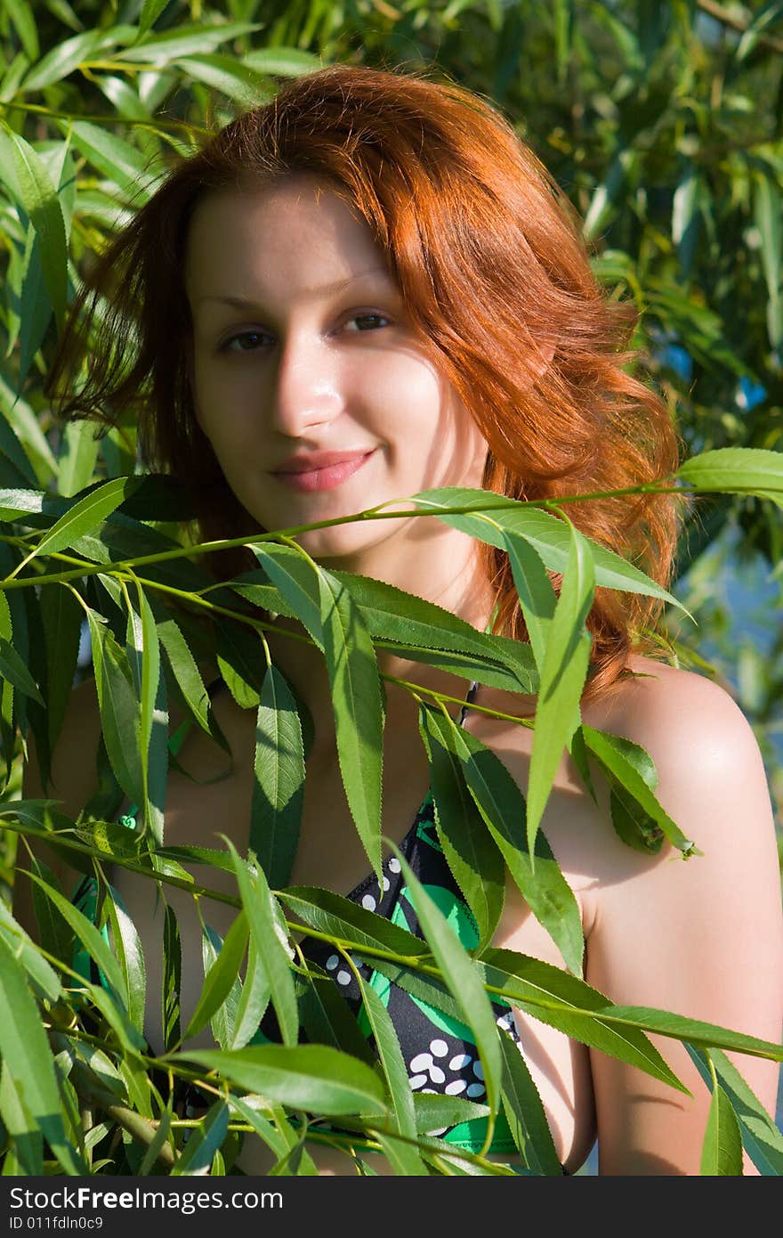 Portrait of the girl among green foliage