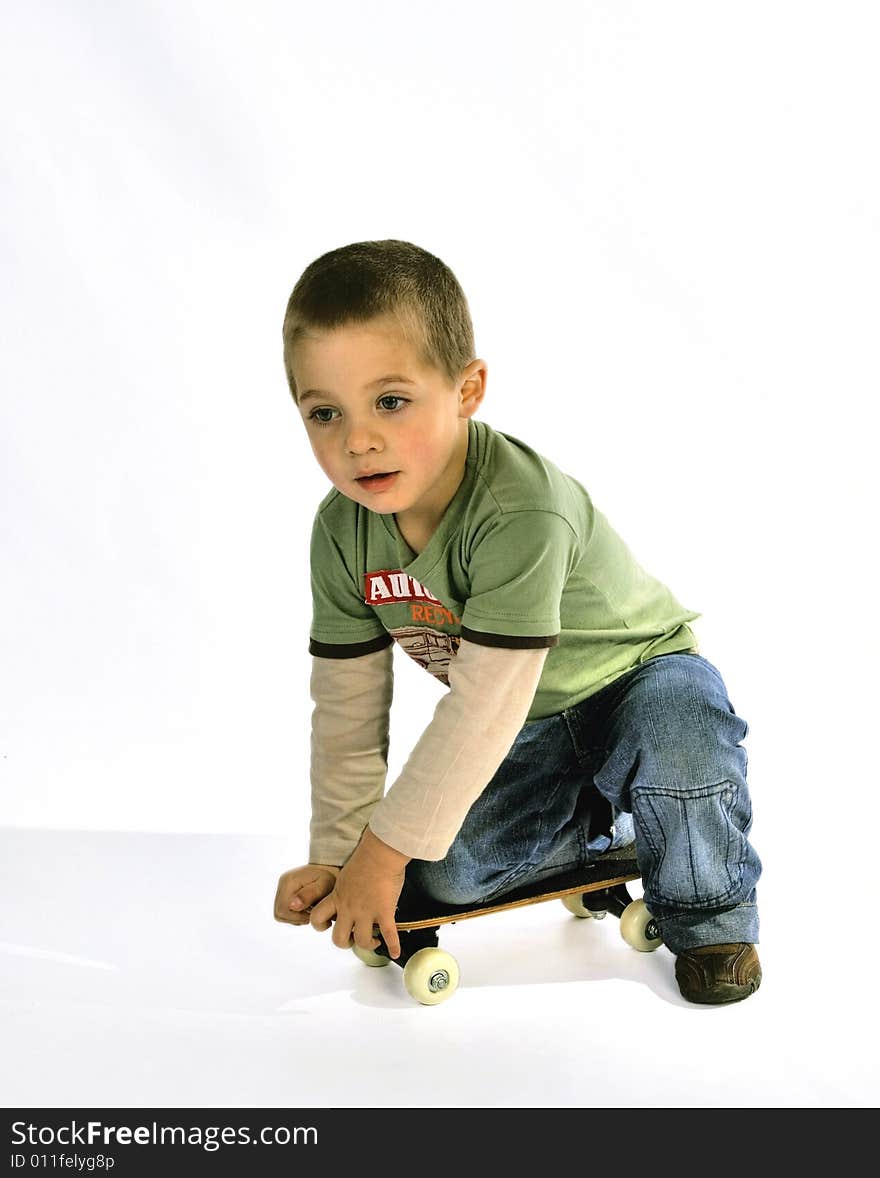 Young boy in a green T-shirt kneeling on a skate board. Young boy in a green T-shirt kneeling on a skate board