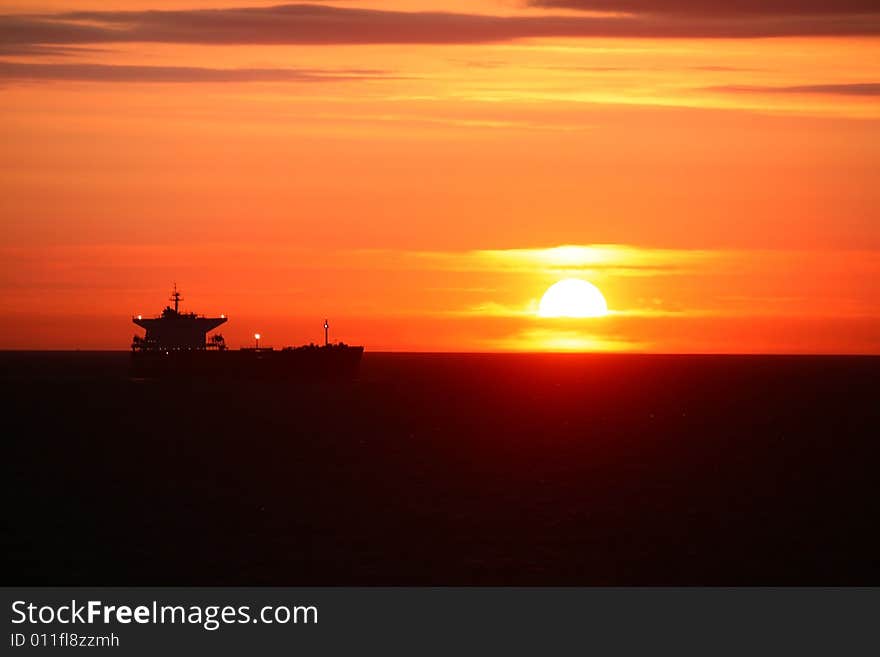 A sunrise on the open sea with ship in the background. A sunrise on the open sea with ship in the background