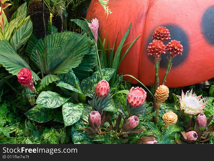 Flowers and fake huge ladybug at a corner of a beautiful garden in summer. Flowers and fake huge ladybug at a corner of a beautiful garden in summer