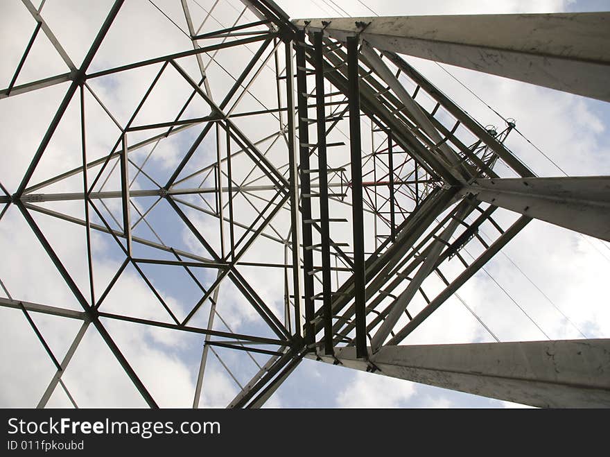 A view to a tower with powerlines, electricity. Picture was taken against a blue sky.