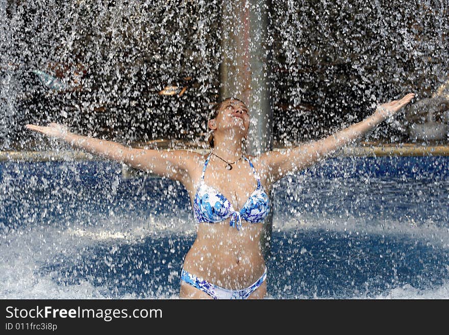 The woman in a bathing suit under jets of water. The woman in a bathing suit under jets of water