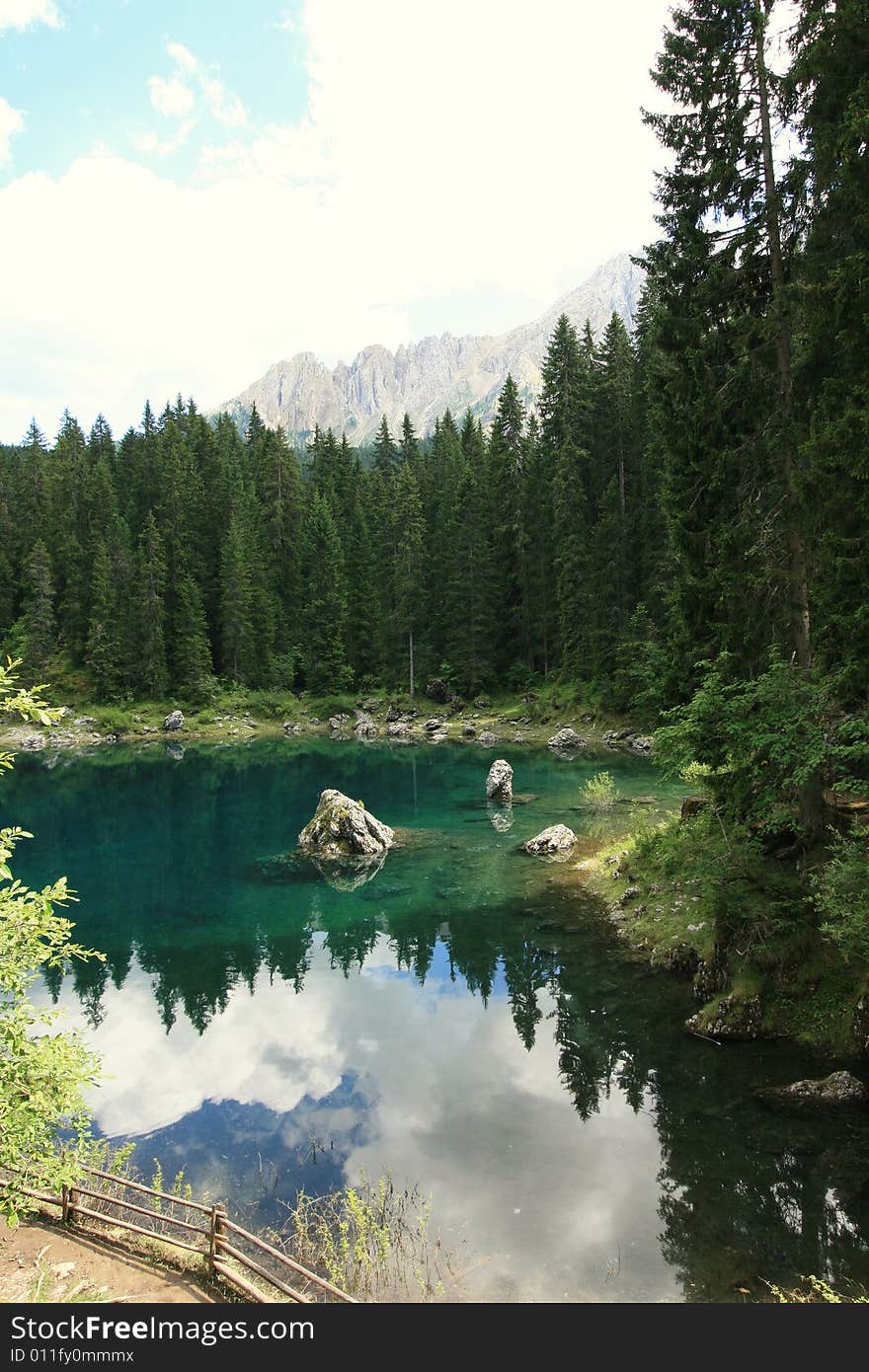 Green pines woods, blue turqoise Carezza  lake & view on Sella montain group, Italy. Green pines woods, blue turqoise Carezza  lake & view on Sella montain group, Italy