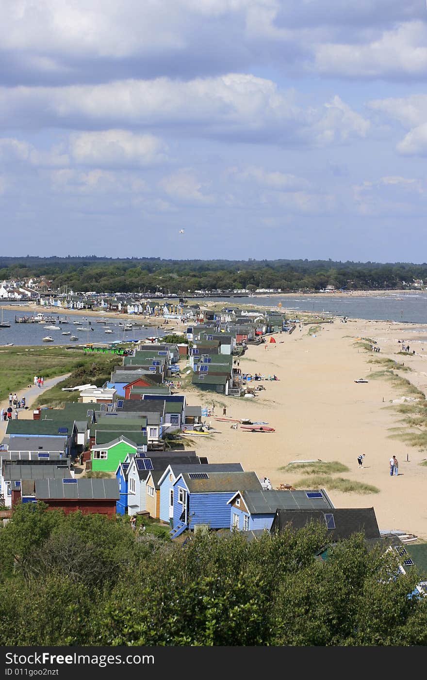 A row of beach huts viewed from Hengisbury Head in Chrustchurch, Dorset UK. Highpoint view from a coastal path. A row of beach huts viewed from Hengisbury Head in Chrustchurch, Dorset UK. Highpoint view from a coastal path.