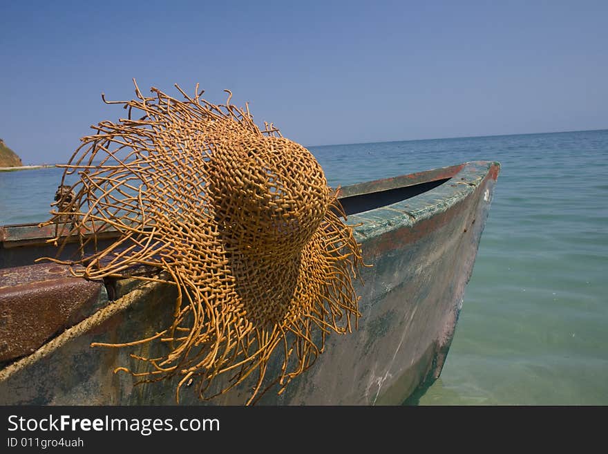 Serene scene with old fishing boat and large straw hat hanging from cleat. Serene scene with old fishing boat and large straw hat hanging from cleat