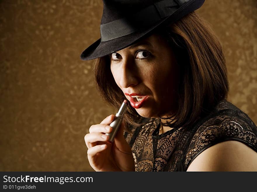 Pretty Hispanic Woman in a Fedora Applying Lipstick. Pretty Hispanic Woman in a Fedora Applying Lipstick