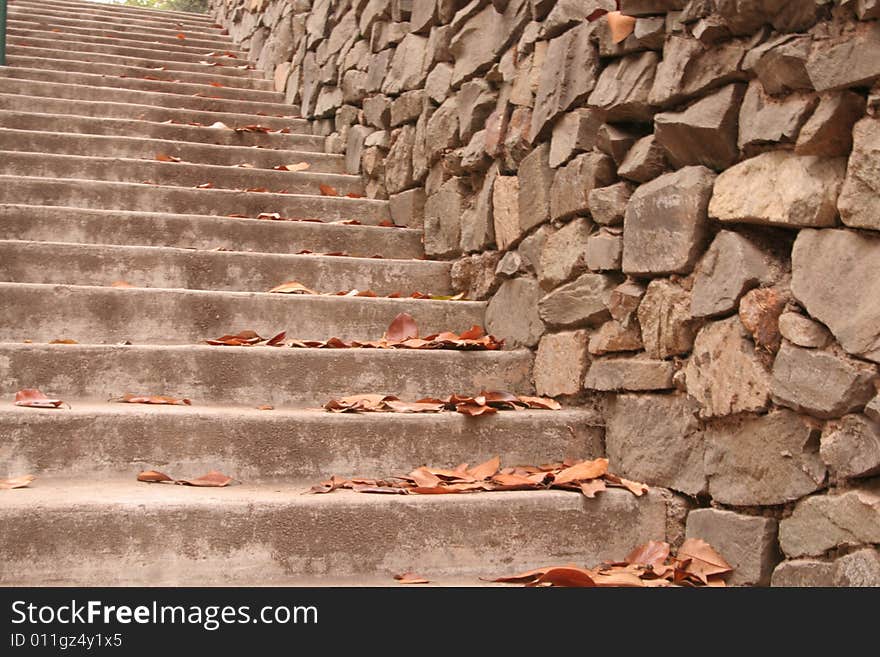 Steep, secluded concrete steps going upward with a rock wall next to it. Lines and patterns. Steep, secluded concrete steps going upward with a rock wall next to it. Lines and patterns.