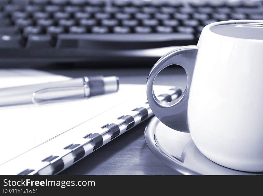 Cup of coffee, keyboard, pen and notebook on a table. Cup of coffee, keyboard, pen and notebook on a table