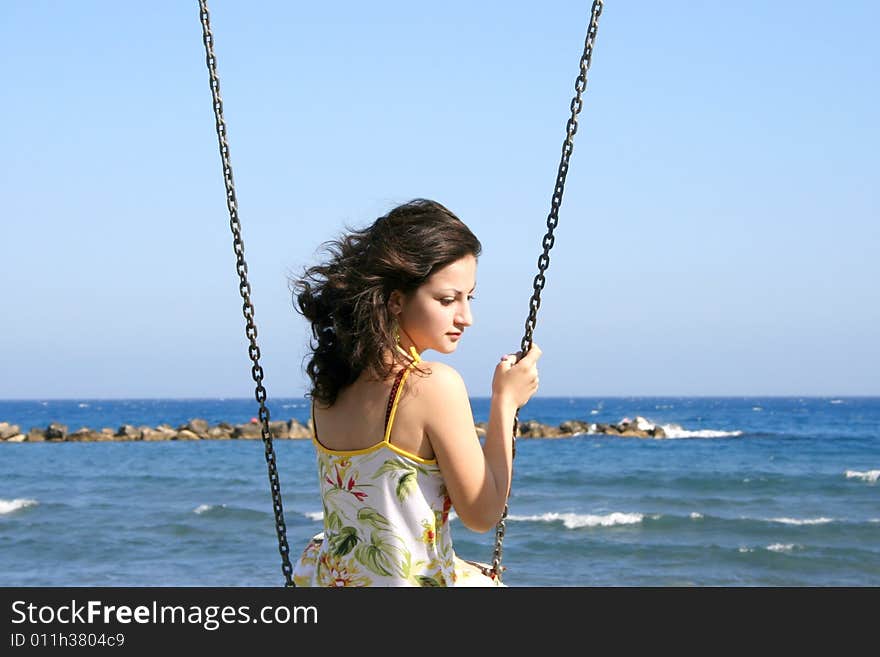 Pretty girl above the sea holding the chain.