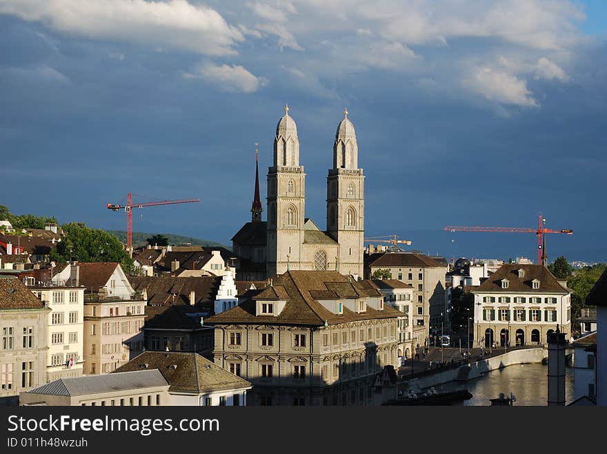 Zurich's Cathedral near the bank of Limmat river surrounded by building cranes