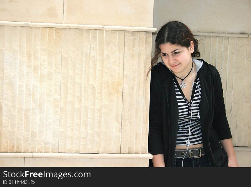 Pretty girl with ear-phones at the wall.