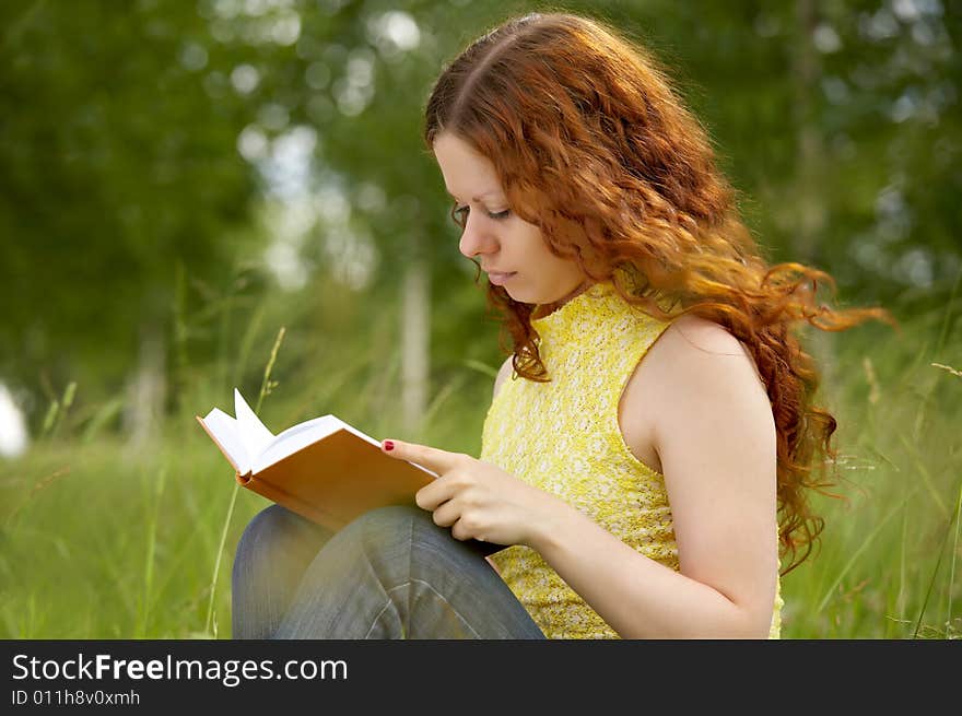 The girl with enthusiasm reads the book in park. The girl with enthusiasm reads the book in park