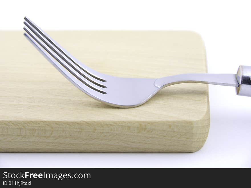 Metal fork and wooden board on white background