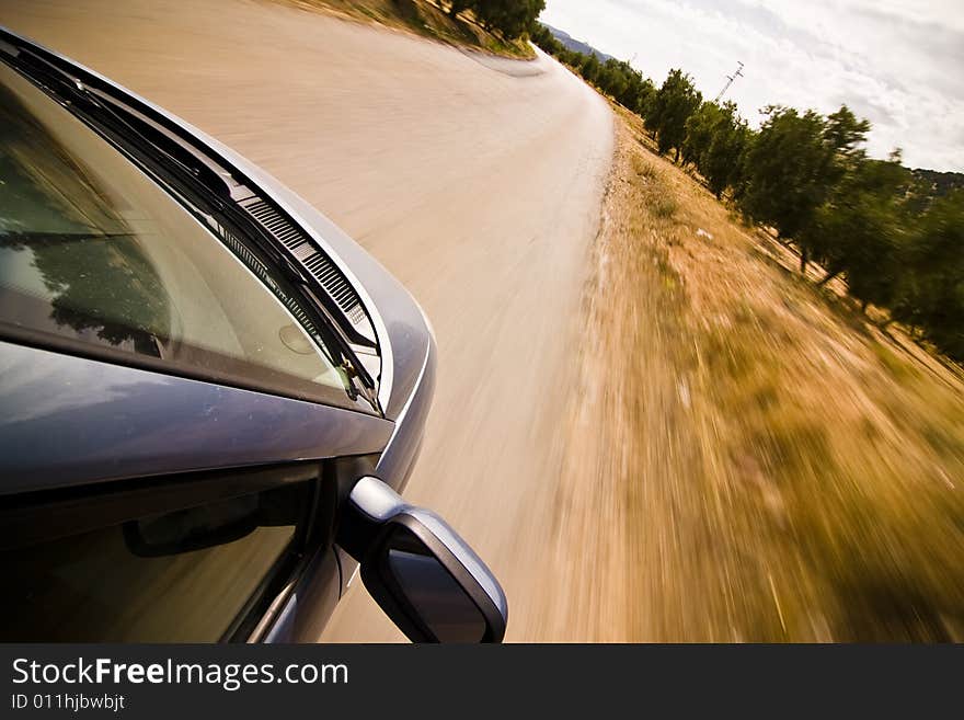 Cruising the countryside in a blue car at high speed.