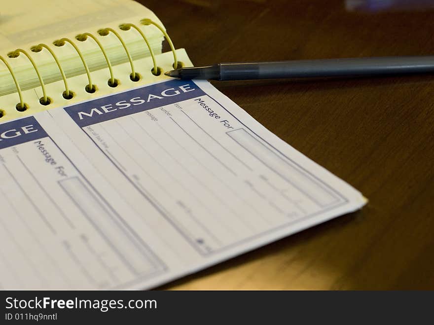 Spiral yellow notepad and black pen on a wooden table. Spiral yellow notepad and black pen on a wooden table.