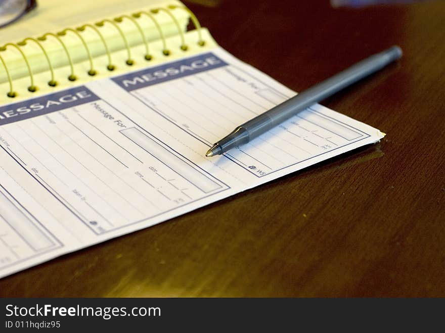 Spiral yellow notepad and black pen on a wooden table. Spiral yellow notepad and black pen on a wooden table.