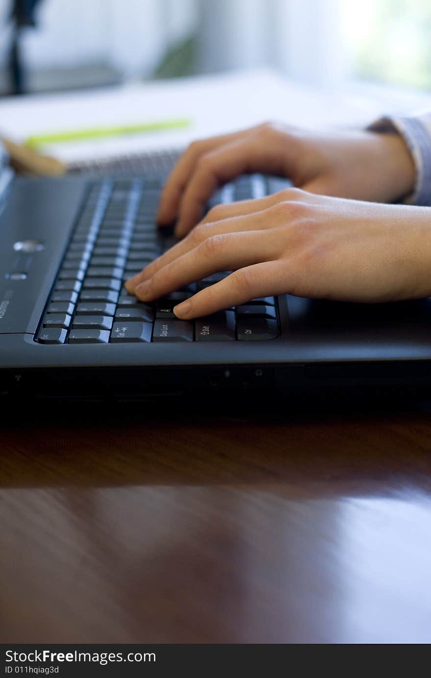 Profile view of hands typing on a black keyboard. Profile view of hands typing on a black keyboard.