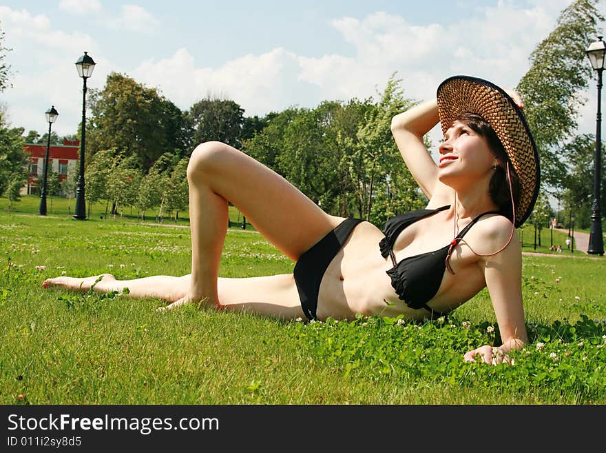 The girl in bikini sunbathes on a green lawn