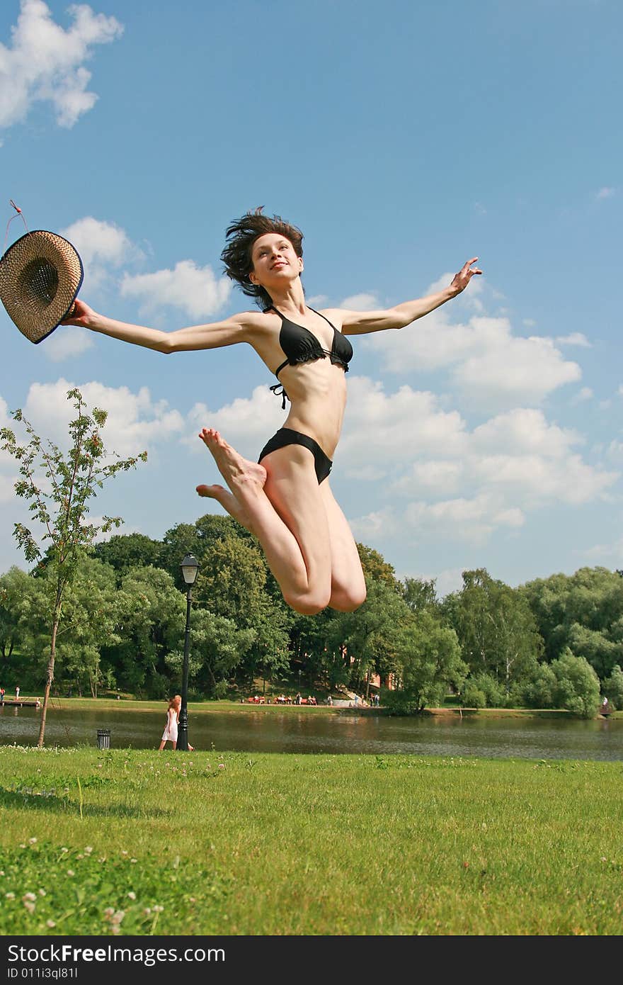 The sports beauty girl in bikini jumps above a lawn. The sports beauty girl in bikini jumps above a lawn