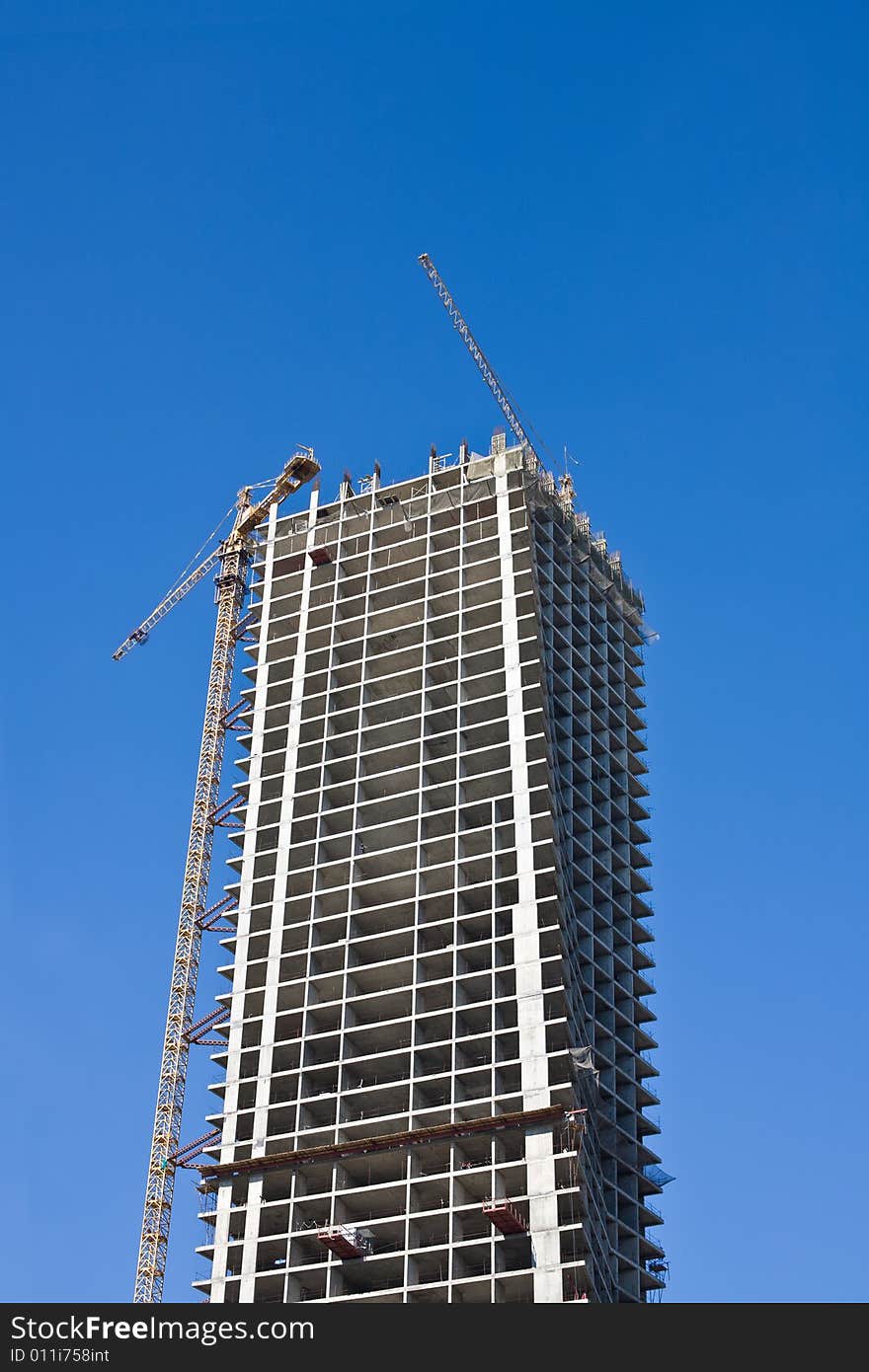 Cranes and building on a background blue sky. Cranes and building on a background blue sky