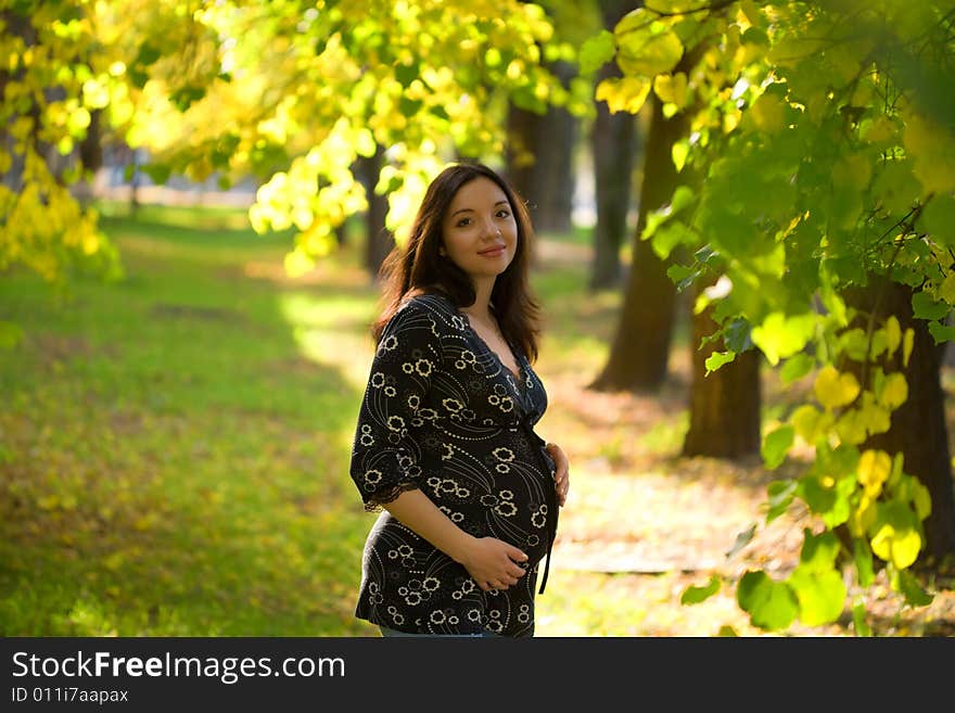 Pleasured pregnant woman do daily promenade in summer park