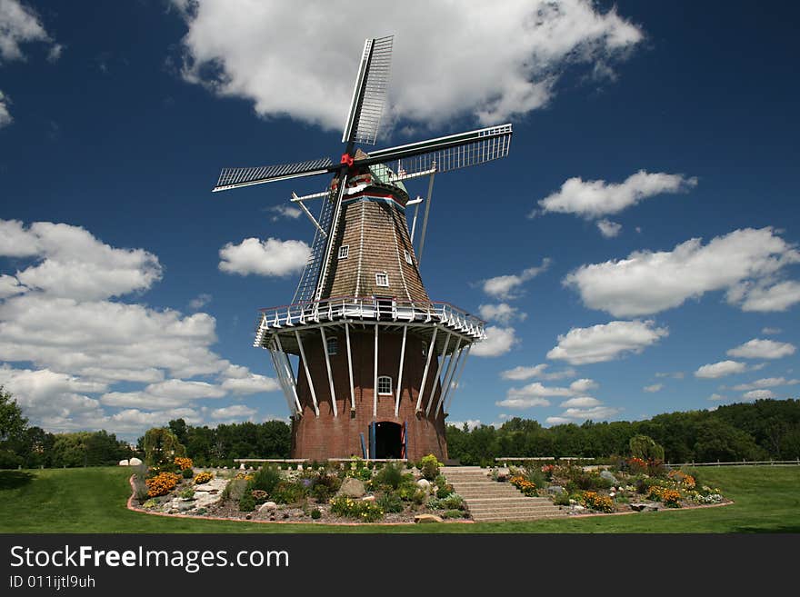 An image of an old Dutch windmill against a blue sky and white clouds