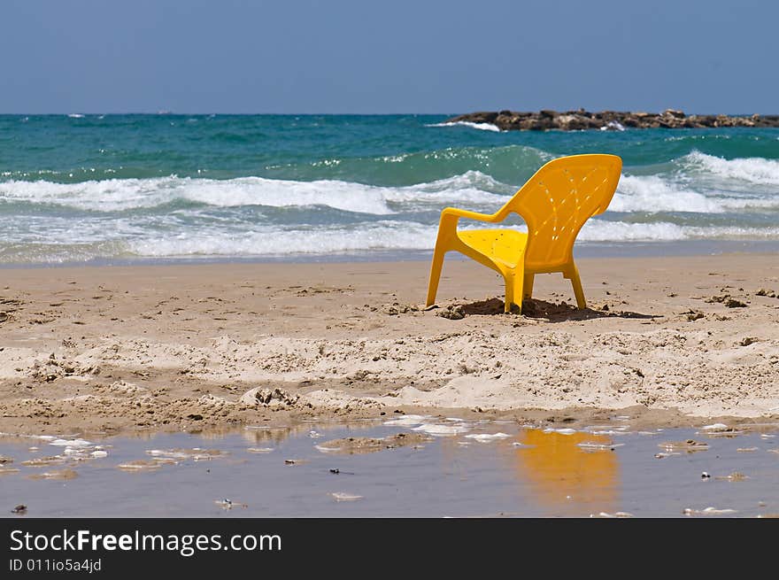 A lonely yellow chair standing on sea beach. A lonely yellow chair standing on sea beach