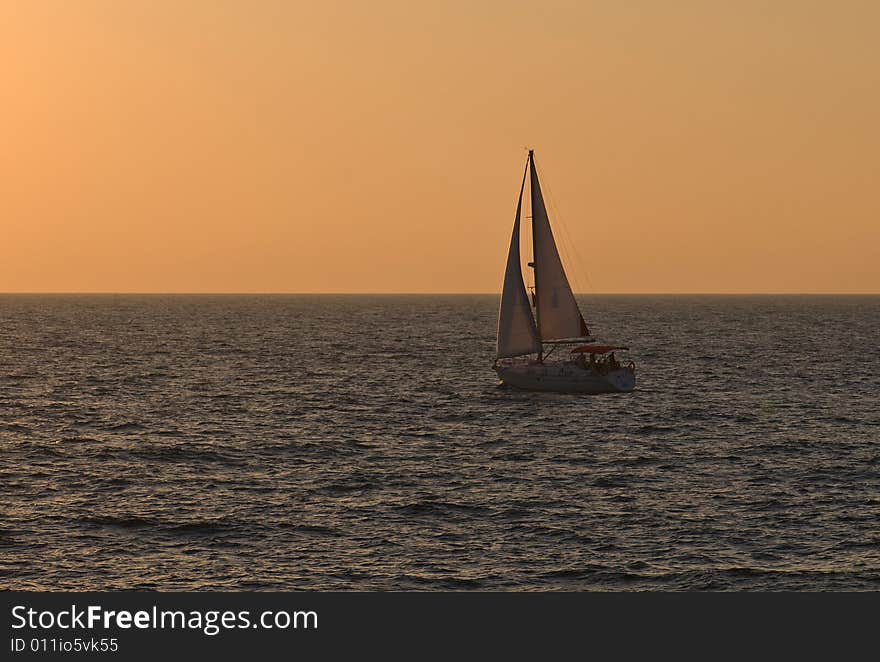 Yacht sailing into beautiful orange sunset. Yacht sailing into beautiful orange sunset